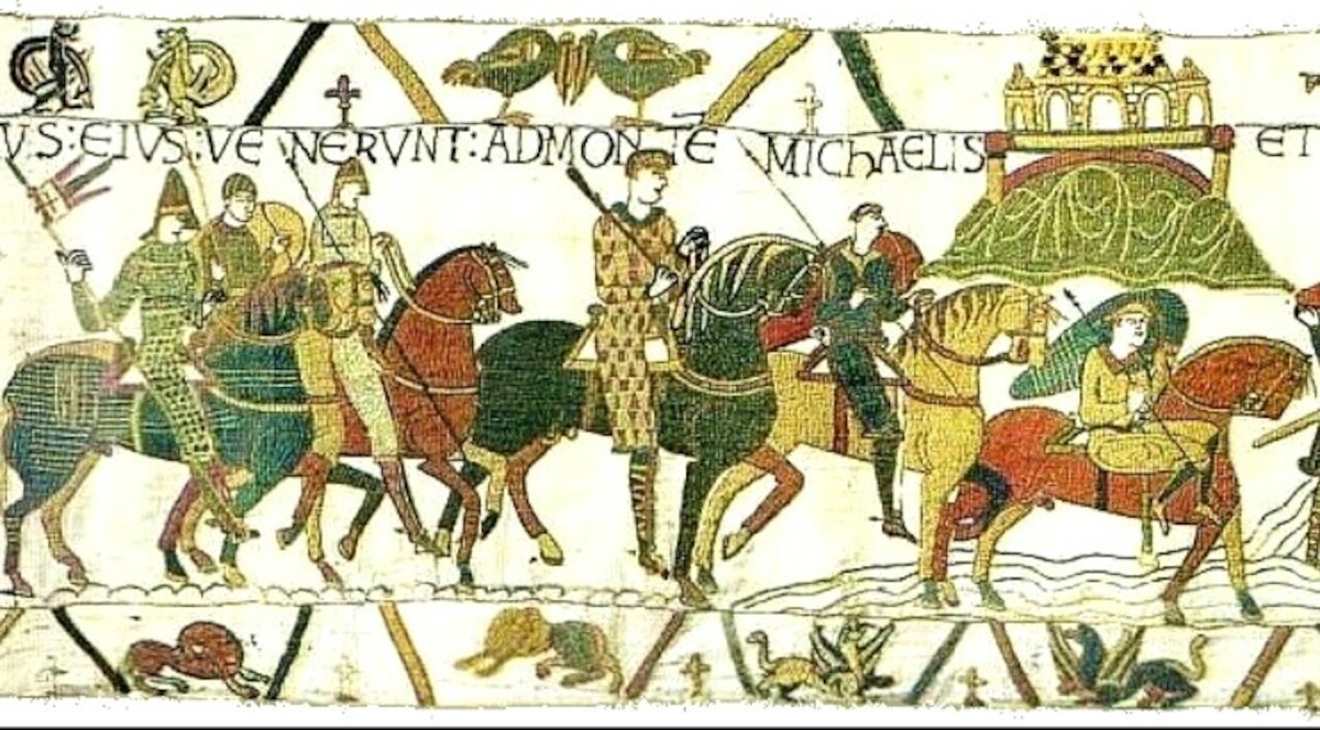 Fragment tkaniny z Bayeux przedstawiający Wilhelma I Zdobywcę i jego armię przybywajacych do klasztoru Mont Saint-Michel .Źródło:<a href='https://pl.wikipedia.org/wiki/Tkanina_z_Bayeux#/media/Plik:BayeuxTapestryScene16.jpg' rel='noopener'>domena publiczna</a>.