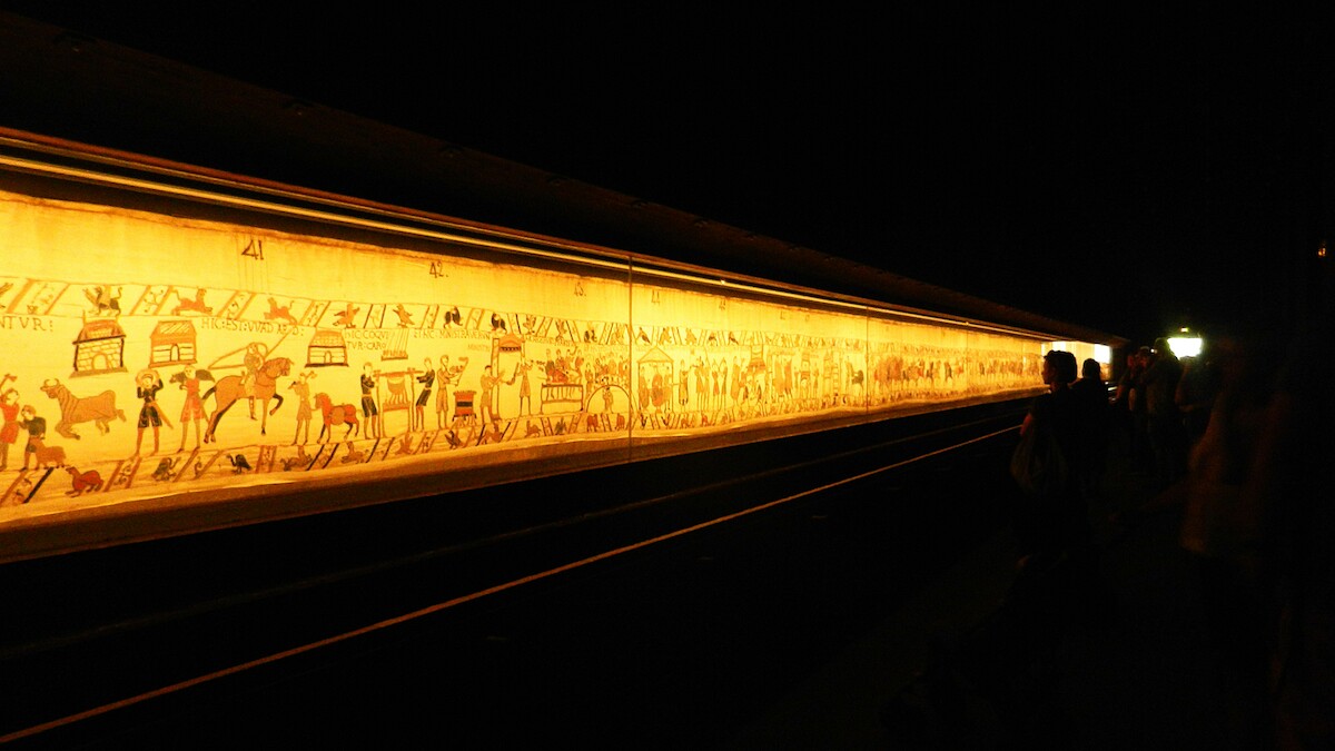 Słynna tkanina w muzeum La Tapisserie de Bayeux. Źródło: <a href='https://pl.wikipedia.org/wiki/Tkanina_z_Bayeux#/media/Plik:Bayeux_Teppich_im_Museum.jpg'>domena publiczna</a>.