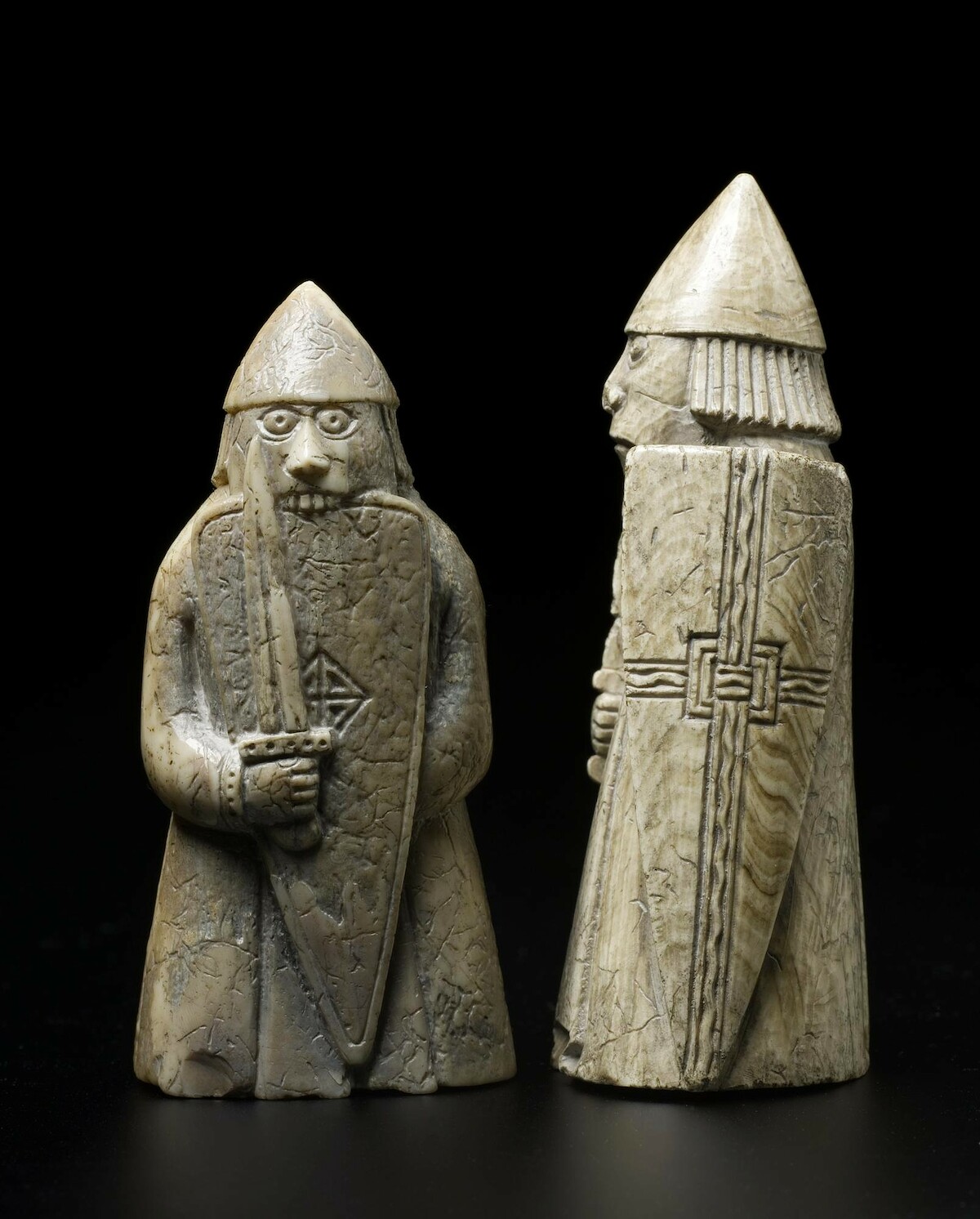 Figurki 'berserkera' i zwykłego strażnika z kompletu szachów z wyspy Lewis (XII w.). Źródło: <a href='https://en.wikipedia.org/wiki/Lewis_chessmen#/media/File:NMSLewisChessmen2.jpg'>domena publiczna</a>.